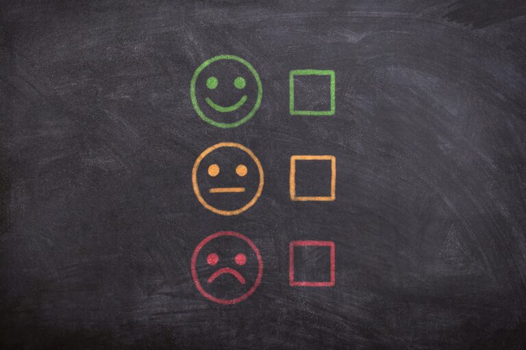 Three faces on a chalkboard, one smiling, one neutral, and one frowning, meant to signify feedback.